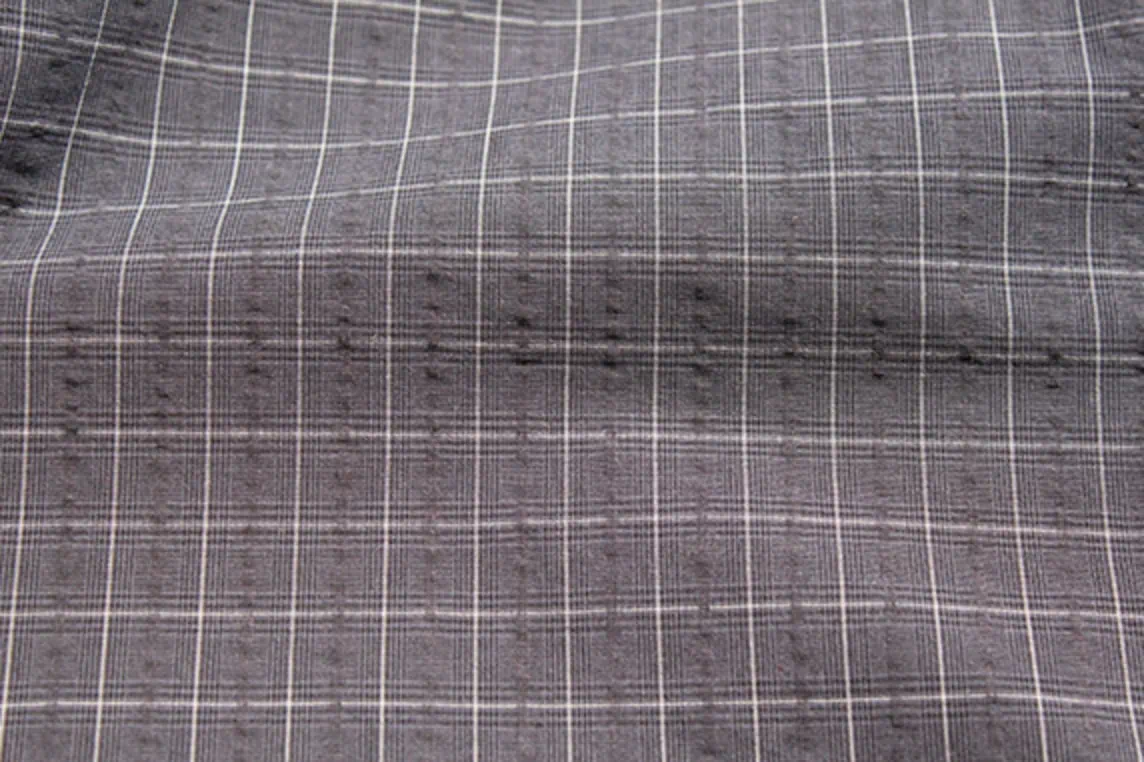 Close-up of lightweight cotton shirting fabric featuring a microscale Glen plaid, windowpane pattern, and seersucker texture