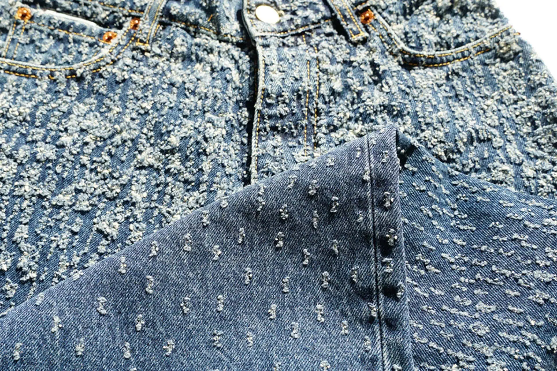 Close-up of jeans with gradient laser distressing, creating a textural ombré effect