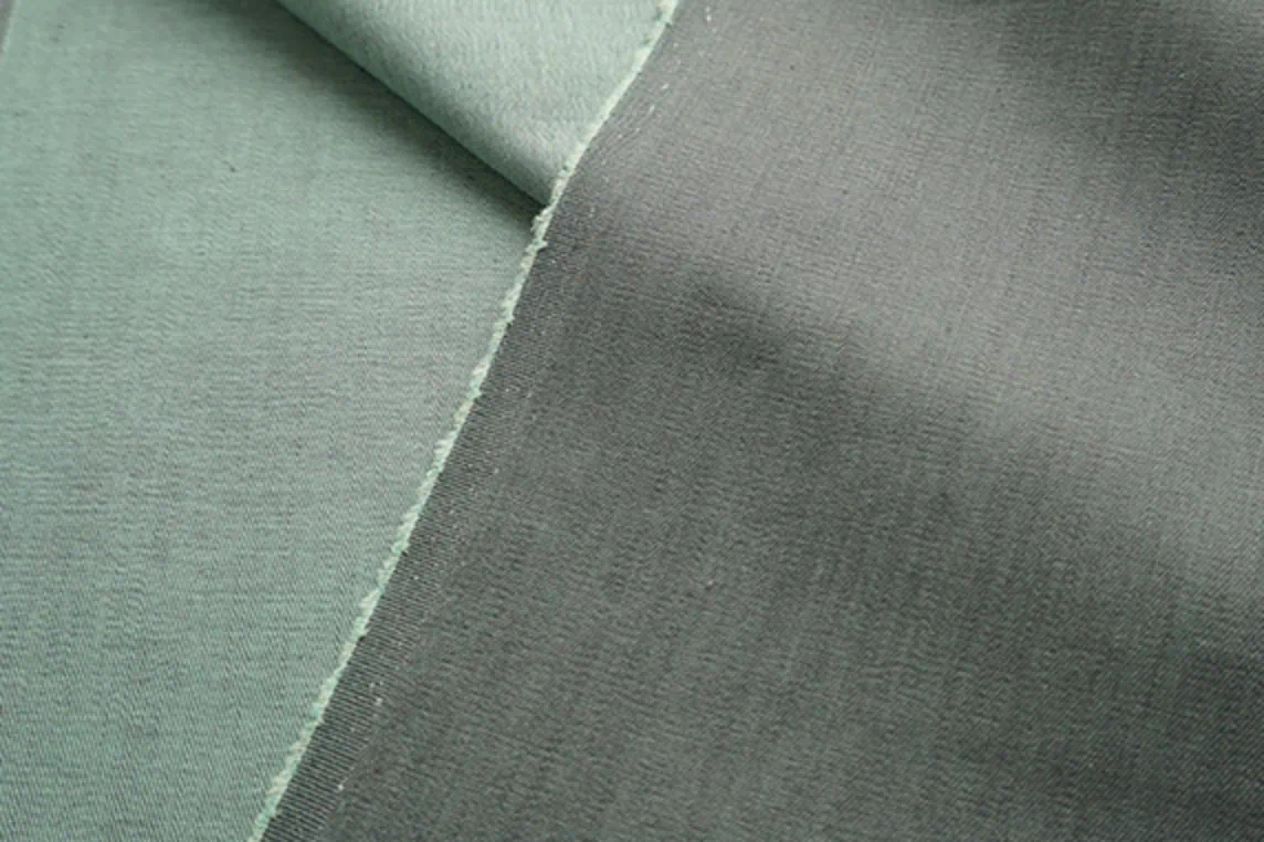 Close-up of lightweight grey denim fabric overdyed in mint green for a hint of color.