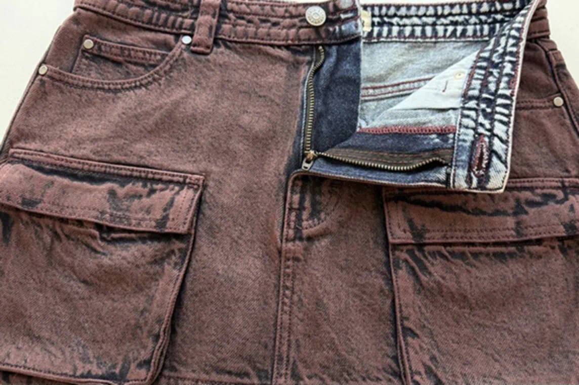 Close-up of indigo denim cargo mini skirt sprayed with maroon pigment